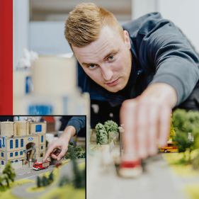 Ein Feuerwehrmann schiebt Miniaturautos durch eine Miniaturwelt