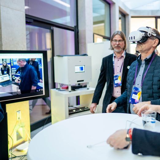 Wirtschaftsminister Dr. Wolfgang Blank blickt durch eine VR-Brille an einem Messestand.