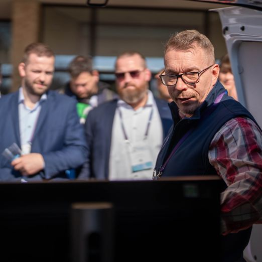 DVZ-Mitarbeiter Sebastian Schriever zeigt den Messebesucherinnen und -besuchern die Car-Forensik-Technik, die in einem Firmenwagen steht.