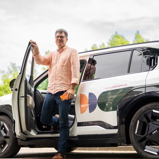 Ein Interamt-Mitarbeiter steigt aus seinem Dienstwagen aus und ist auf dem Weg zum Kundentermin