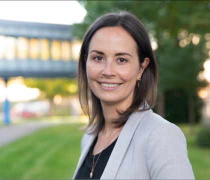 Portrait: Annemarie Guse, DVZ-Ausbildungskoordinatorin, steht vor dem Hauptgebäude des DVZ und lächelt in die Kamera.