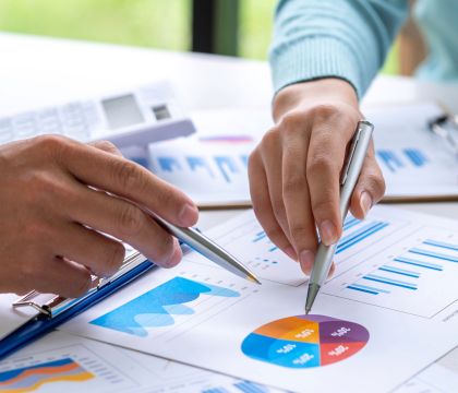 Zwei Hände mit Stift zeigen auf ein Diagramm auf einem Blatt Papier