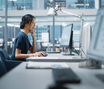 Eine Frau im Büro sitzend schaut auf ihrem Monitor