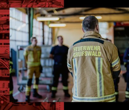 Feuerwehrleute stehen in einem Kreis in einer Halle