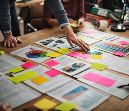Arbeit mit ausgedruckten Papieren und Post-its auf einem Tisch