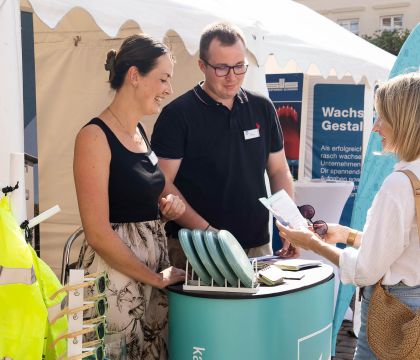 Drei Personen unterhalten sich an einem Karrierestand des DVZ