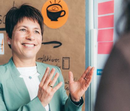 Change Managerin Romy Reitz erklärt etwas vor einer Metaplanwand.
