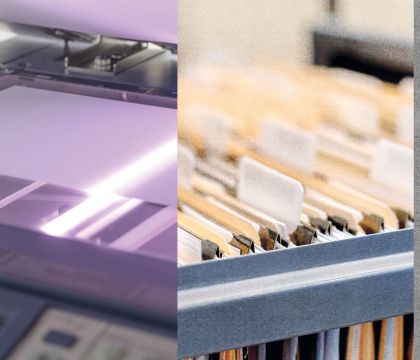 Ein geöffneter Scanner, auf dem ein Blatt Papier gerade gescannt wird und verschiedene sortierte Akten in einer Schublade.